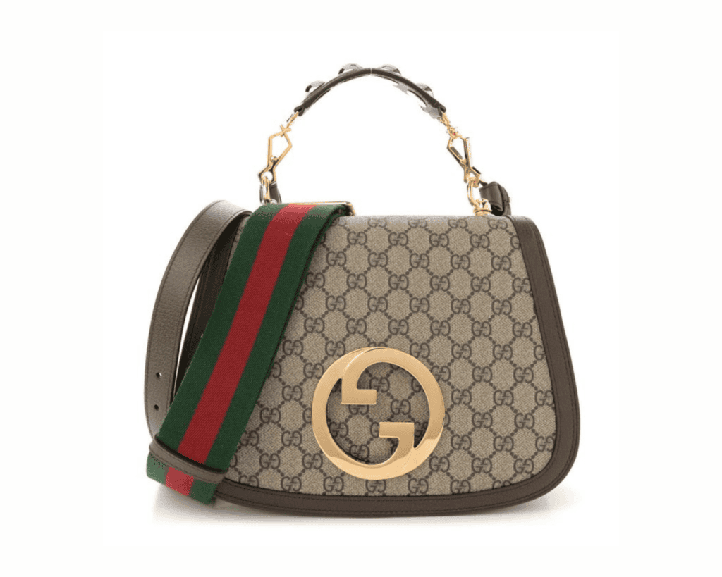 Gucci Blondie medium top handle bag in beige and ebony GG Supreme canvas with brown leather trim, a large gold-tone round interlocking G logo, a studded leather handle, and a green and red Web strap.