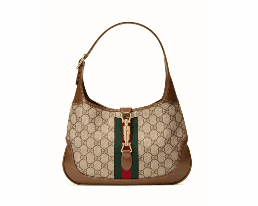 Gucci Jackie 1961 small shoulder bag in beige and ebony GG Supreme canvas with brown leather trim, a vertical green and red Web stripe, and a gold-tone piston closure.