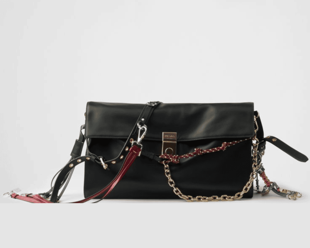 Prada Soft Sound large leather shoulder bag in black smooth leather featuring colorful detachable charms, a gold-tone chain link strap, and a central engraved metal push-lock clasp.