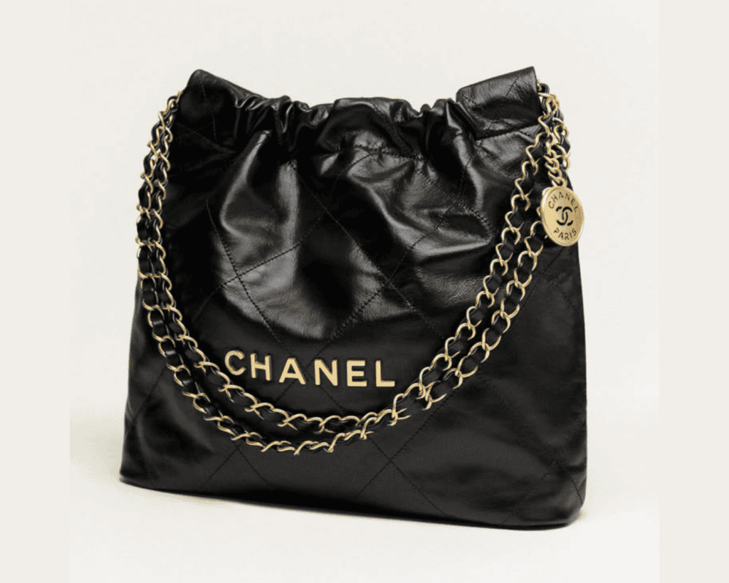 Chanel 22 small tote bag in black shiny crumpled calfskin leather with gold-tone metal CHANEL block letters and woven chain strap featuring a signature CC medallion.