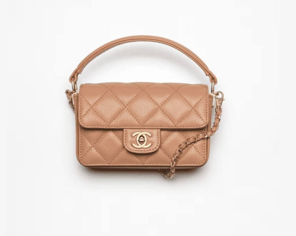 Chanel mini top handle flap bag in beige quilted caviar leather featuring a curved leather top handle, an interlocking gold CC turnlock, and a thin woven chain strap.