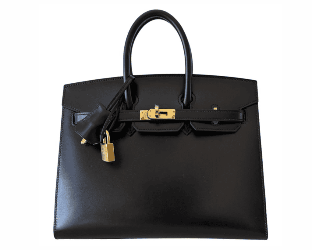 A studio front shot of a structured black Hermès Birkin 25 handbag crafted from smooth, high-shine Box calfskin leather, detailed with two rolled top handles, polished gold-tone metal turnlock hardware, and a hanging leather clochette with a matching gold padlock.