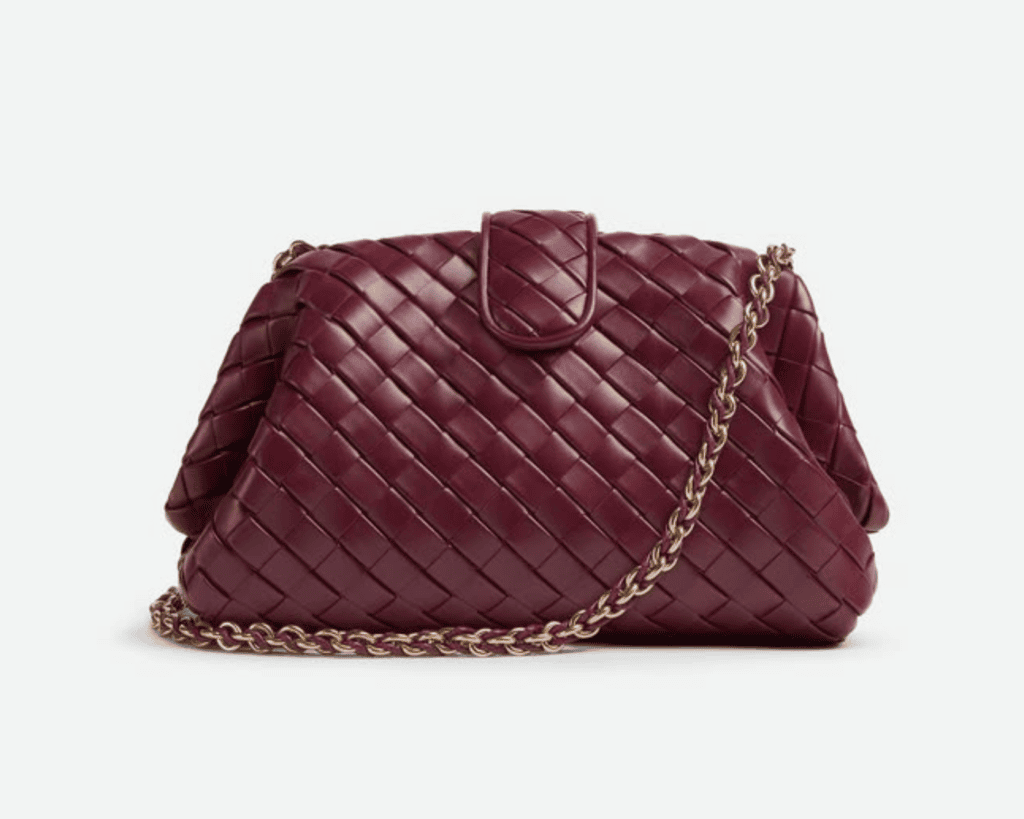 A studio front shot of a deep wine-red "Barolo" Bottega Veneta Teen Lauren 1980 clutch bag, featuring a hand-woven padded Intrecciato leather frame, a matching magnetic leather fold-over tab closure, and a coordinating gold-toned tubular leather-braided metal chain strap draped in front.