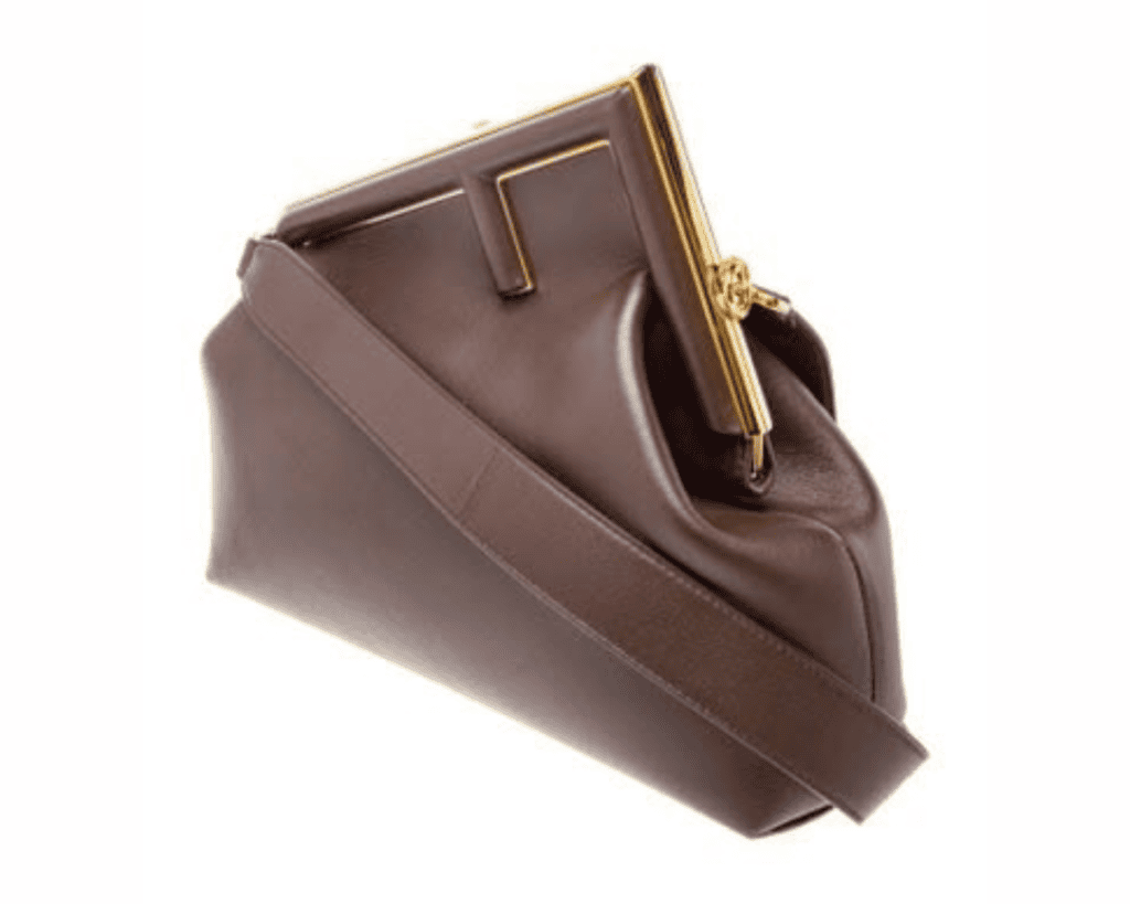 A dark brown nappa leather Fendi First shoulder bag featuring a tilted metal frame shaped like a capital letter "F" at the clasp closure The RealReal, with a wide matching brown leather shoulder strap draped across the front.